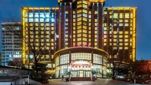 A multi-story hotel with a prominent curved entrance and illuminated windows. - Xuanwei Meihuan Hotel (Xuanwei)