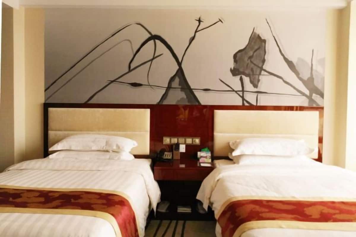 A hotel room with two beds, a large abstract wall art, and a nightstand with a lamp.
