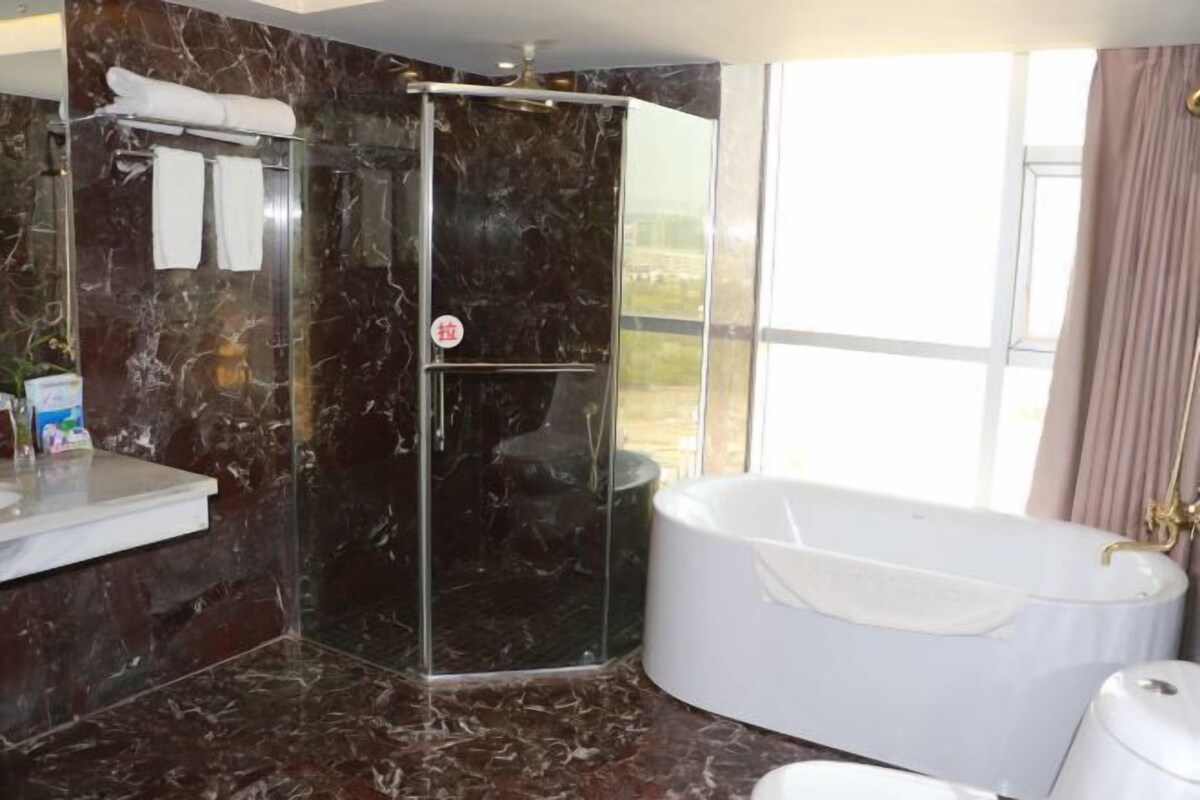 A bathroom with a glass-enclosed shower, a white bathtub, and a marble floor.