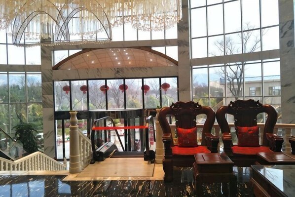 A lobby with a glass wall, a staircase, and a reception desk.