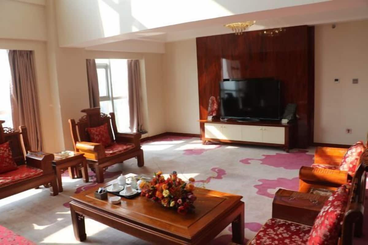 A living room with a sofa, chairs, a coffee table, a TV, and a decorative vase.