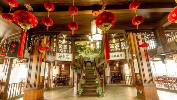A traditional interior with wooden beams, red lanterns, and a central staircase. - Xuanwei Meihuan Hotel (Xuanwei)