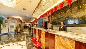 A hotel reception area with a marble counter, red stools, and a receptionist. - Xuanwei Meihuan Hotel (Xuanwei)