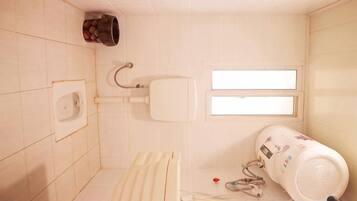 A small, tiled bathroom with a toilet, a hand dryer, and a water heater.