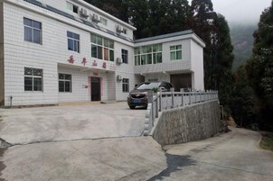 A two-story building with a flat roof, a car parked in front, and a paved driveway leading to the entrance.