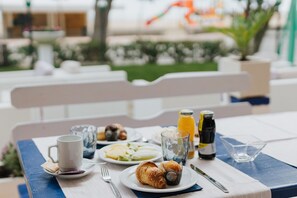 Una mesa de desayuno con croissants, una taza, un vaso de zumo de naranja y una botella de agua.