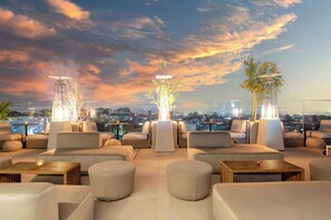 A rooftop lounge with modern seating and a city view.