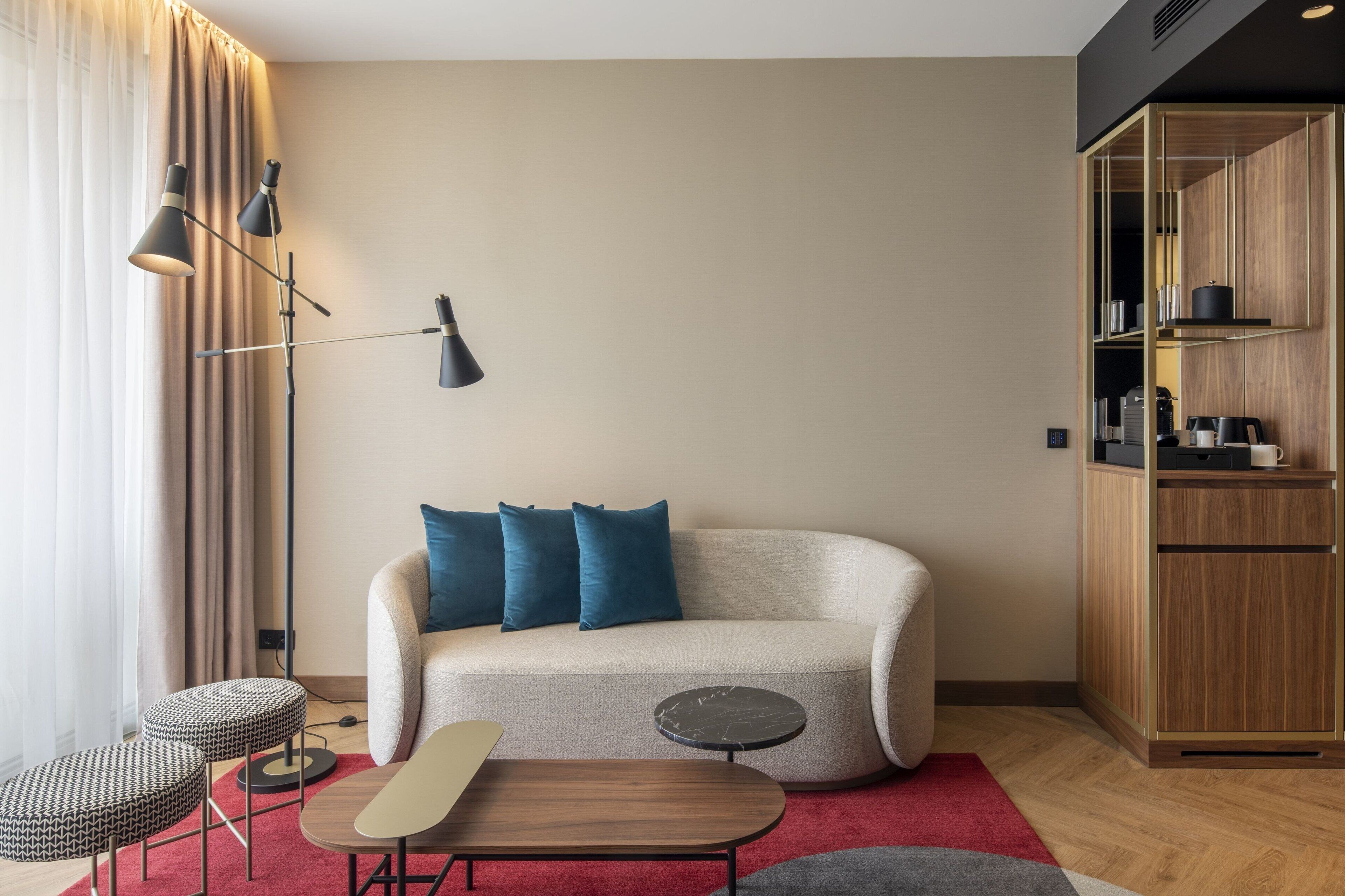 A modern living room with a sofa, two side tables, a red rug, and a tall floor lamp.