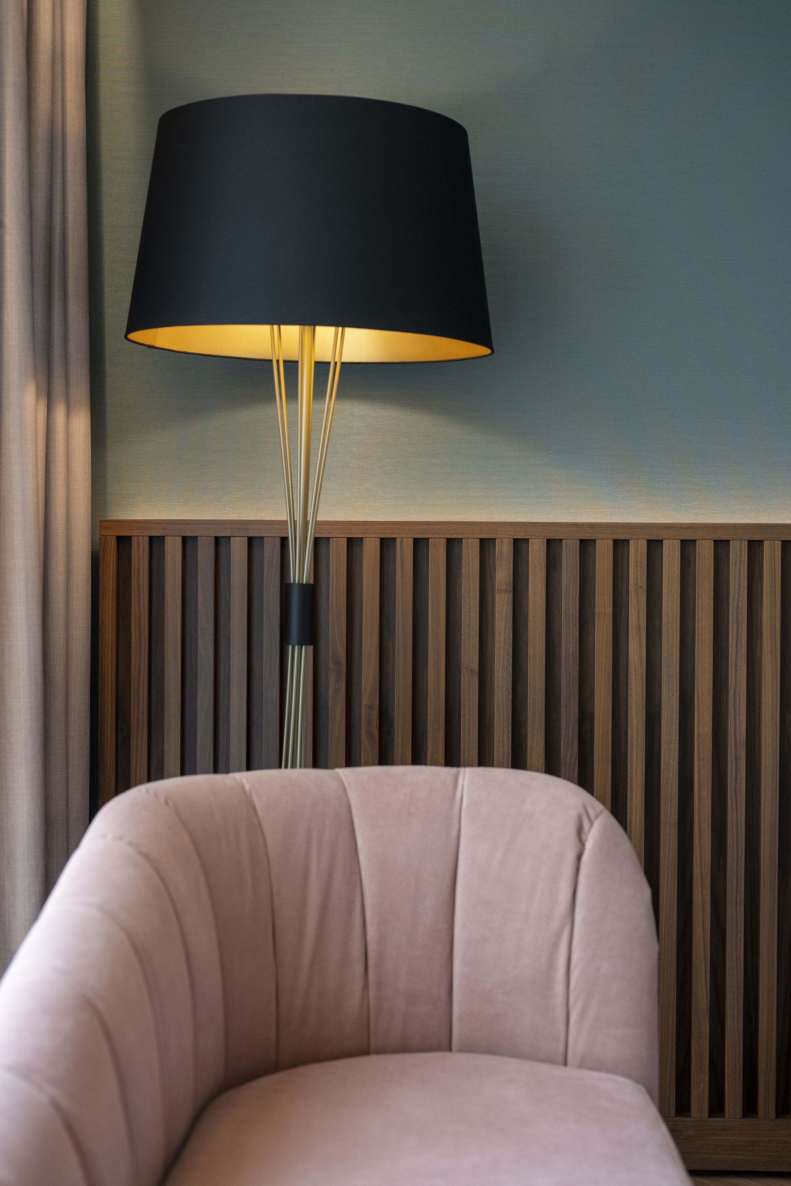A modern room with a curved sofa, a floor lamp, and a wooden panel wall.