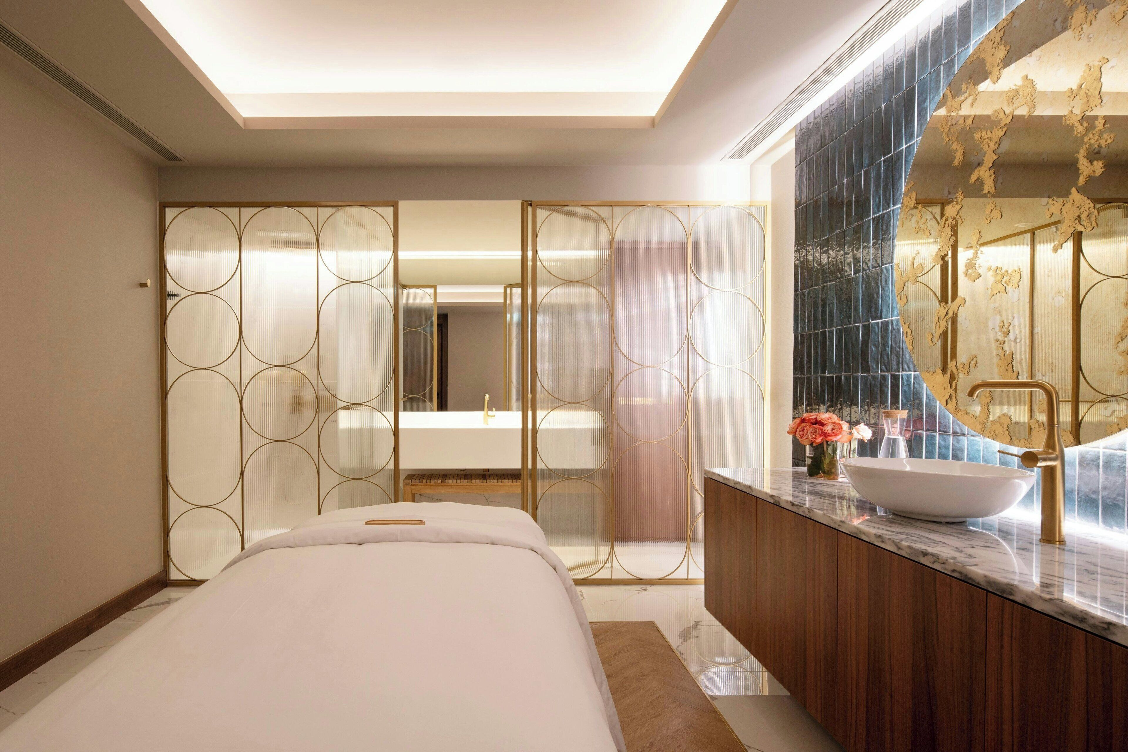 A modern hotel room with a large bed, a bathroom with a large mirror, and a wooden vanity.