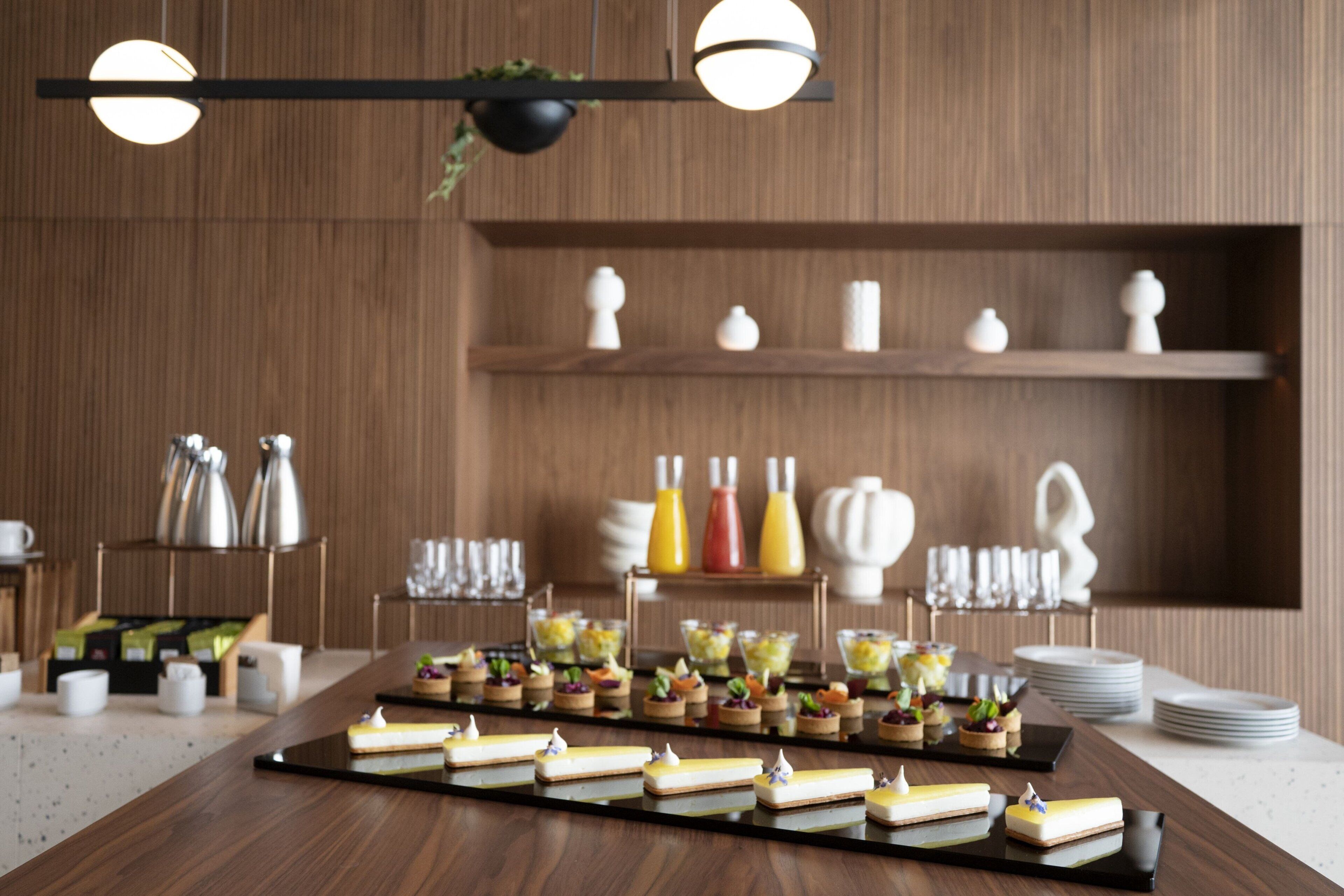 Una mesa de buffet con diversos alimentos y una selección de salsas y aderezos en estantes al fondo.