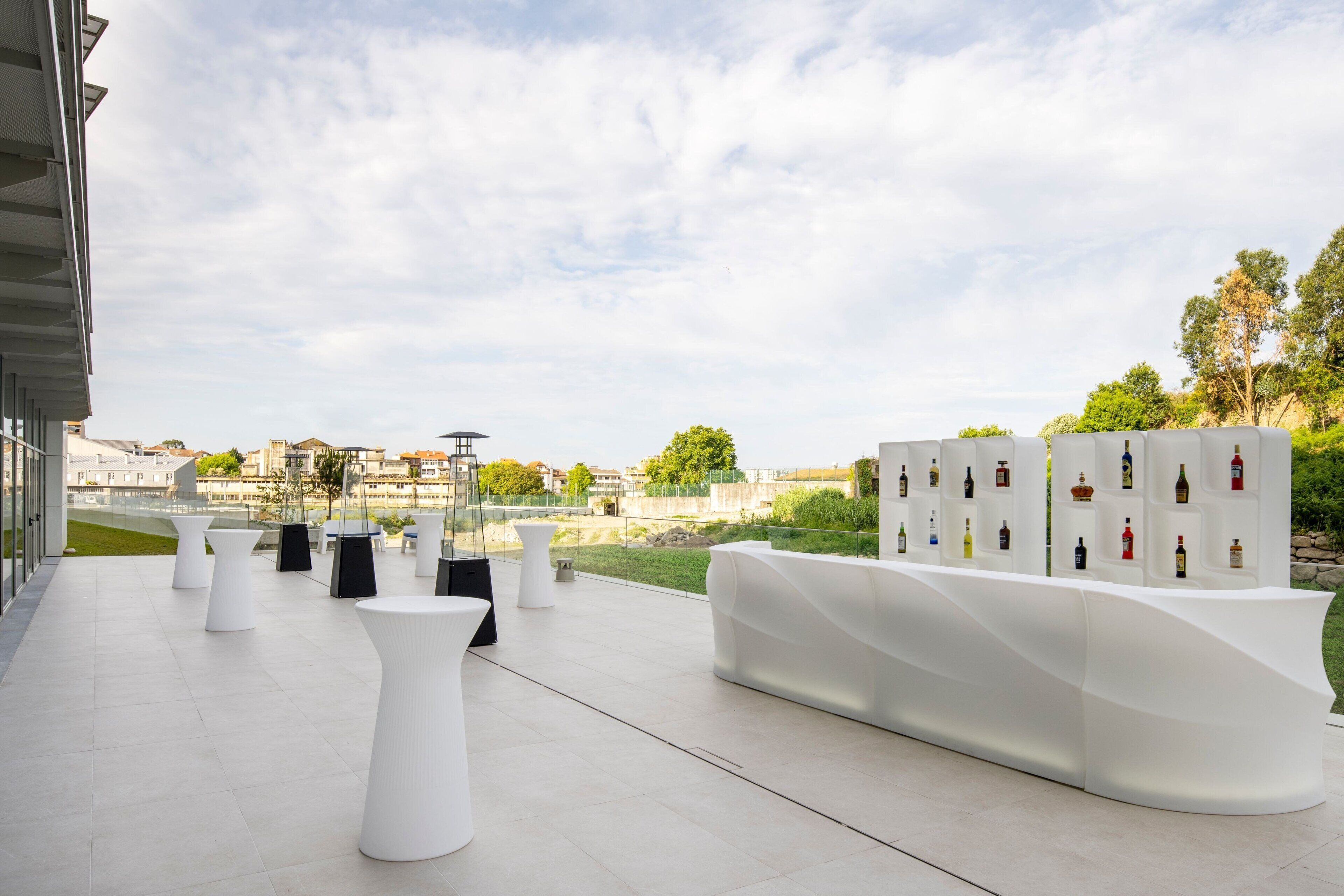 An outdoor terrace with white furniture and a wall of wine bottles.