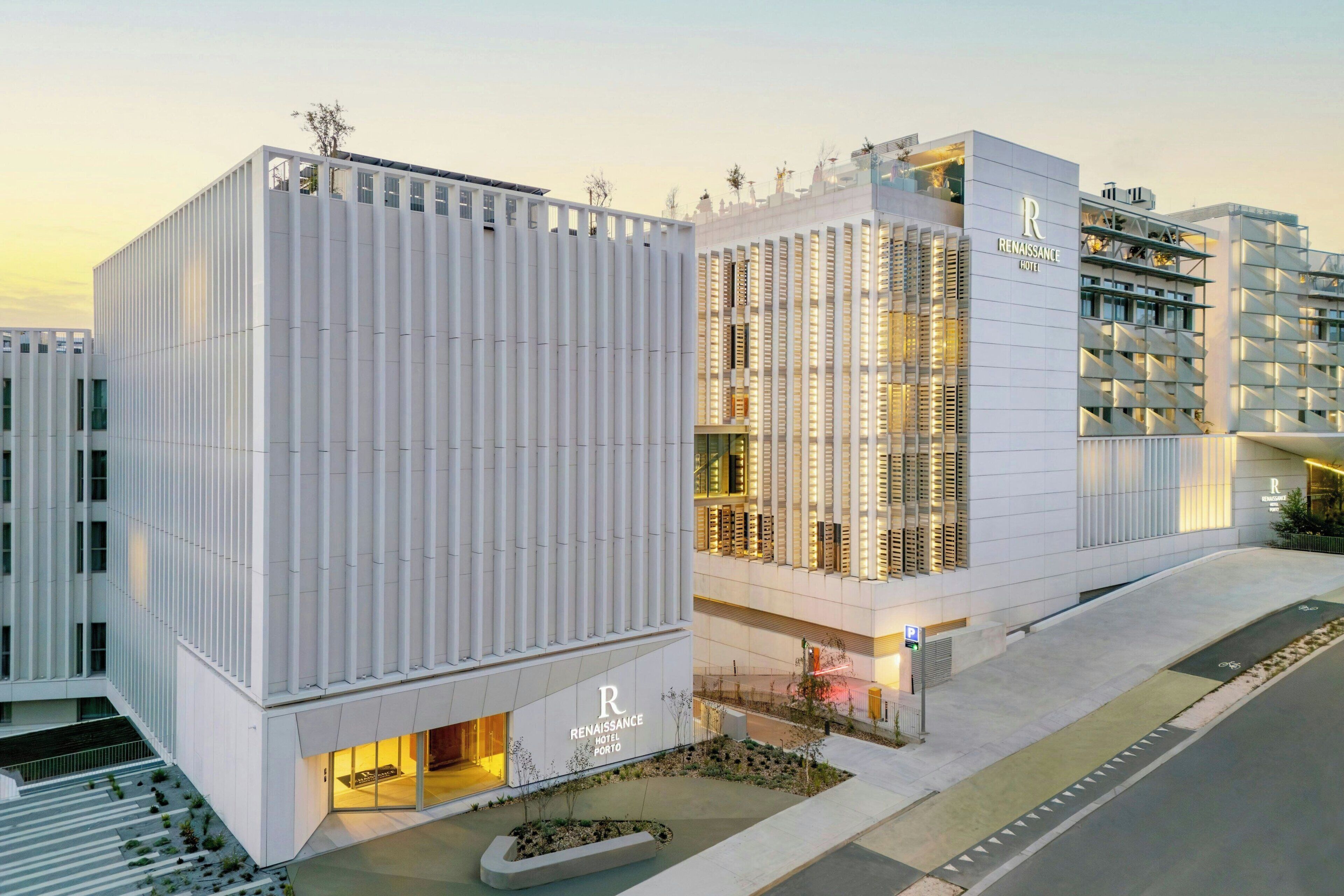 Un hotel moderno con un llamativo letrero que dice 'Renaissance Hotel Porto', con fachada blanca y limpia, líneas verticales y techo plano.