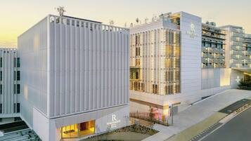 Un hotel moderno con un llamativo letrero que dice 'Renaissance Hotel Porto', con fachada blanca y limpia, líneas verticales y techo plano.