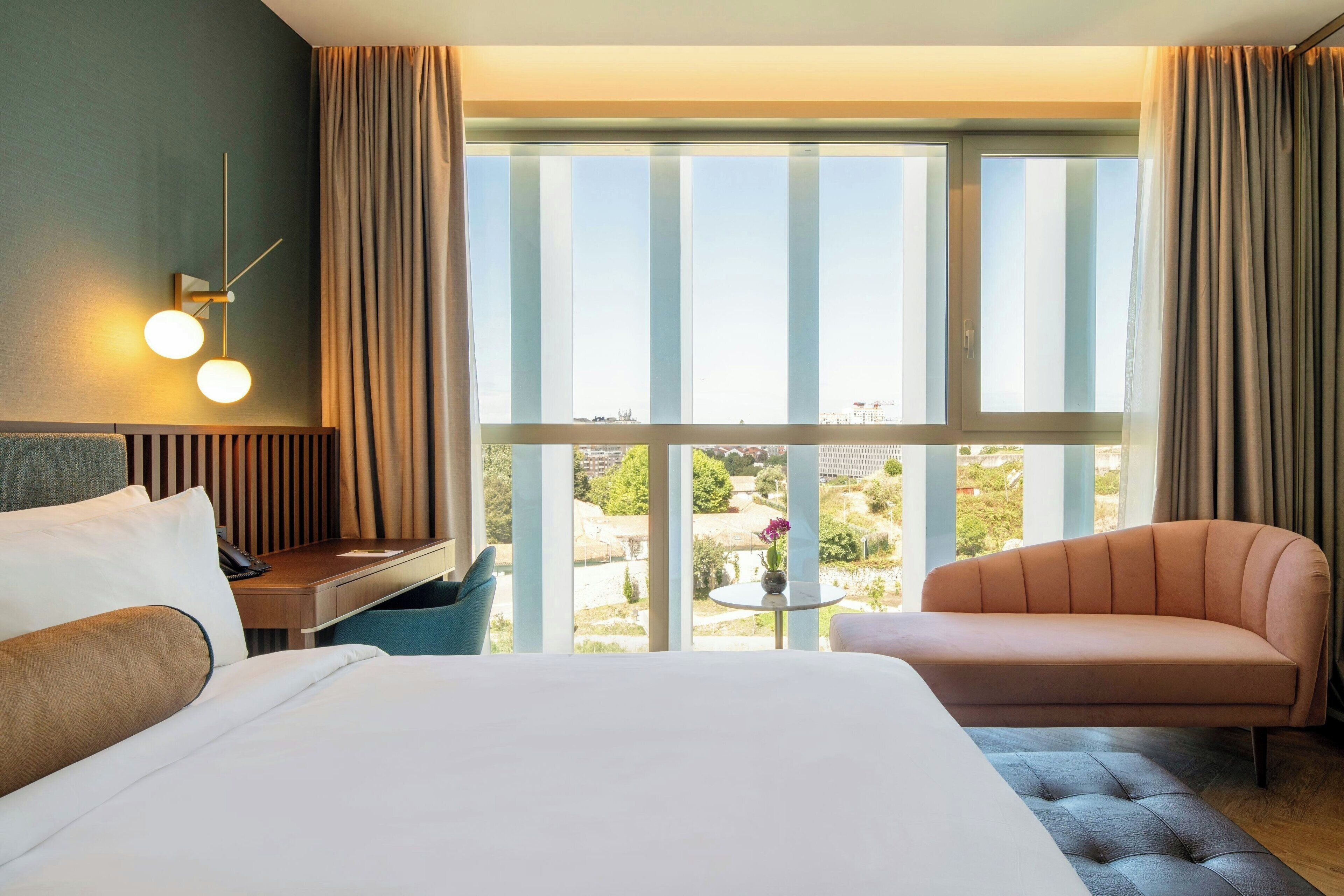 Une chambre d’hôtel avec un lit, un canapé, un bureau et une vue sur l’extérieur.