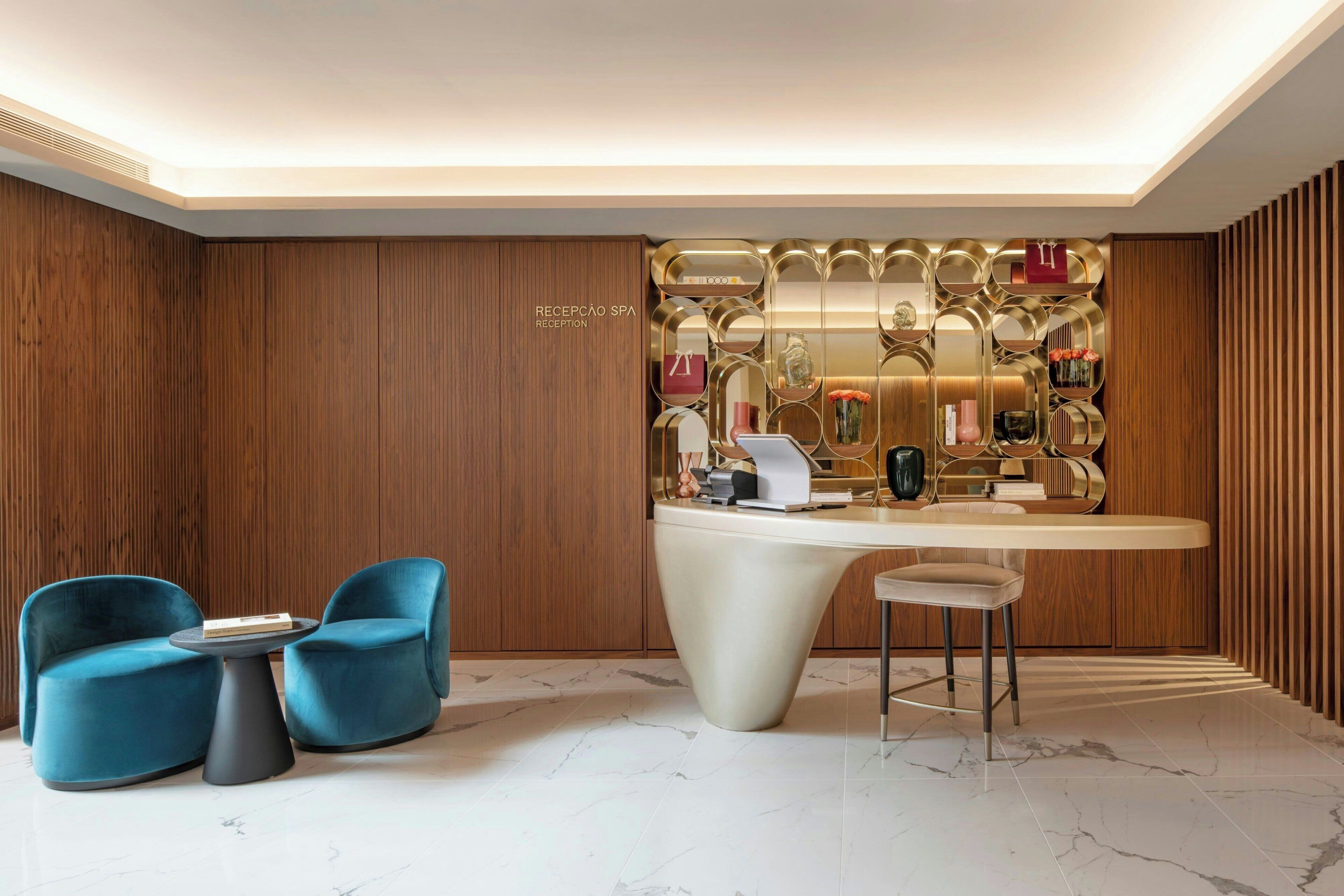 A modern reception area with a wooden panel wall, a reception desk, and two blue chairs.