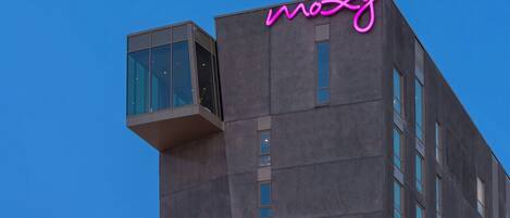 Un edificio moderno con un llamativo letrero de neón rosa que dice