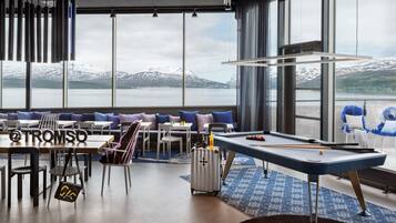 Un espace de détente moderne comprenant une table de billard, des sièges et une vue sur un lac et des montagnes.