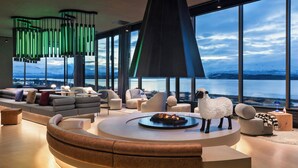 A modern living room with a circular seating area, large windows, and a view of a lake.