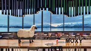 A restaurant with a large table, chairs, and a sheep sculpture.