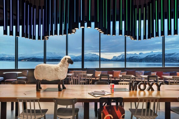 Un restaurant avec une grande table, des chaises et une sculpture de mouton.