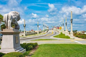 A statue of a lion on a pedestal, a curved road with traffic signs, and a clear sky. - Anastasia Adventure 2 (St. Augustine)