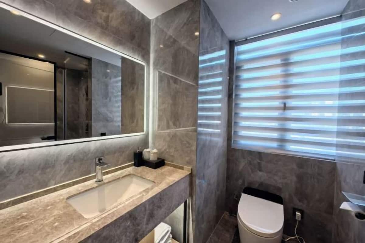 A modern bathroom with a large mirror, a sink, and a toilet.
