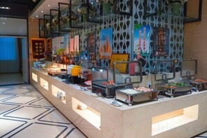 A buffet setup with various food items and a decorative wall with patterns. - Tianyi Mingdu Mansion (Longyao County)