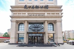 Entrada de un hotel con un amplio frente de vidrio en arco y un cartel que dice "TIANXI MIJIDU RESTAURANT".