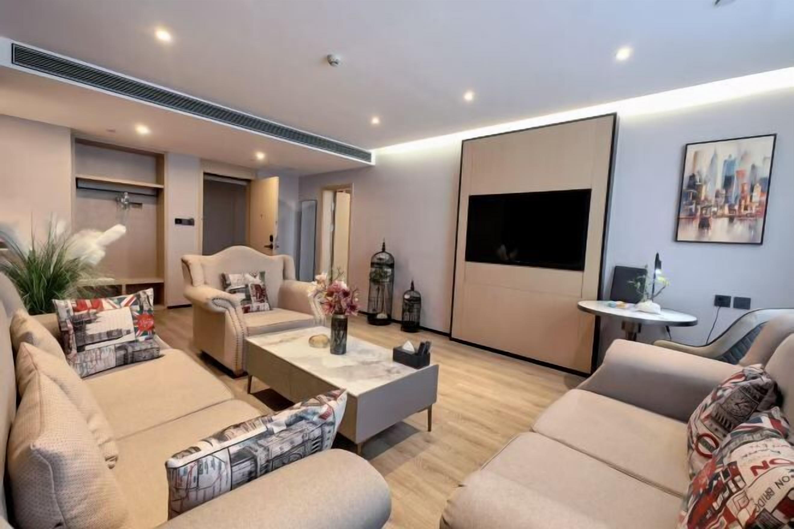 A modern living room with a sofa set, a coffee table, and a flat-screen TV mounted on the wall.