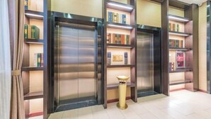 A lobby with a modern design, featuring a central elevator surrounded by bookshelves. - Tianyi Mingdu Mansion (Longyao County)