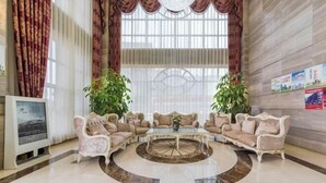 A spacious lobby with a marble floor, two sofas, a coffee table, and large windows with curtains. - Tianyi Mingdu Mansion (Longyao County)
