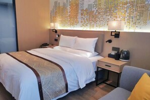 A hotel room with a large bed, a nightstand, a lamp, and a wall art piece.