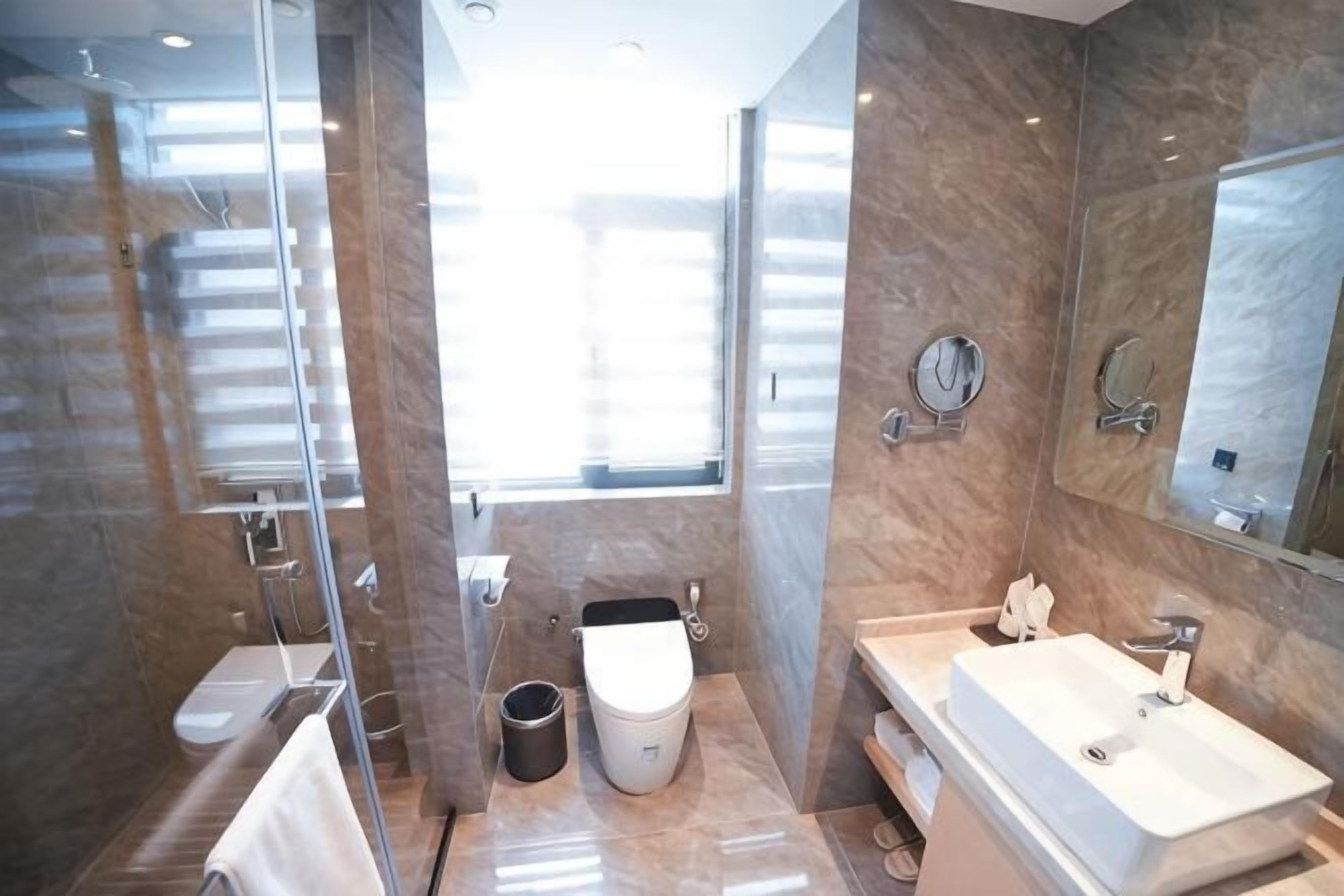 A modern bathroom with a glass shower enclosure, a toilet, a sink, and a large mirror.