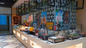 A buffet setup with various food items and a person serving. - Tianyi Mingdu Mansion (Longyao County)