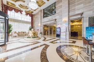 A hotel lobby with a circular seating area, a reception desk, and a large chandelier.