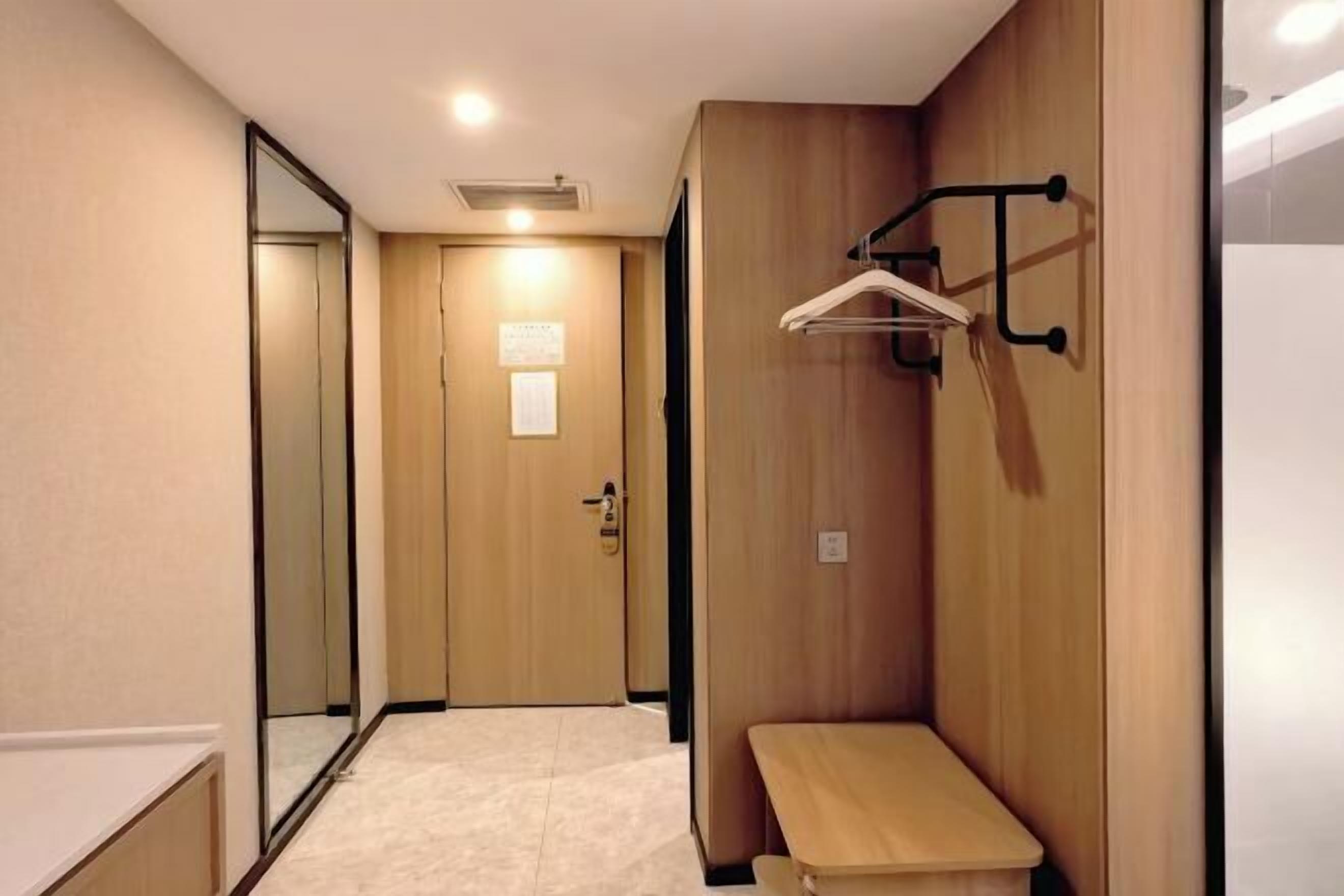 A hallway with a wooden bench, a coat rack, and a door with a sign.