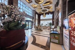 A hotel lobby with a reception desk, a large potted plant, a fountain, and a view of the entrance. - Tianyi Mingdu Mansion (Longyao County)