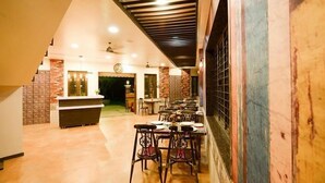 A restaurant with a modern interior, featuring a long counter, multiple tables, and a variety of chairs. - Shri Vitthal Mangalam (Satara)