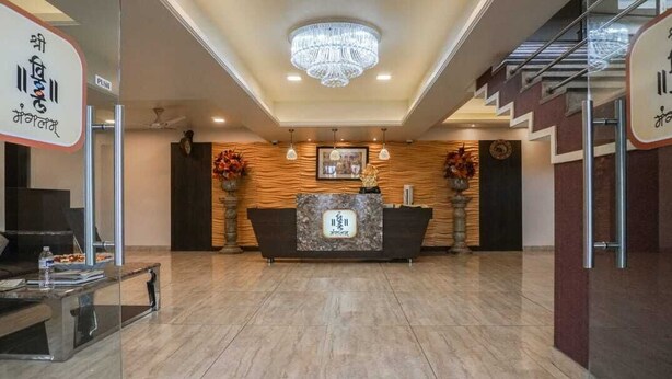 A reception area with a marble counter, a chandelier, and a staircase. - Shri Vitthal Mangalam (Satara)