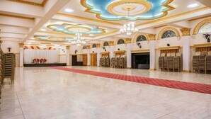 A spacious hall with a red carpet, tiered seating, and ornate ceiling designs. - Shri Vitthal Mangalam (Satara)
