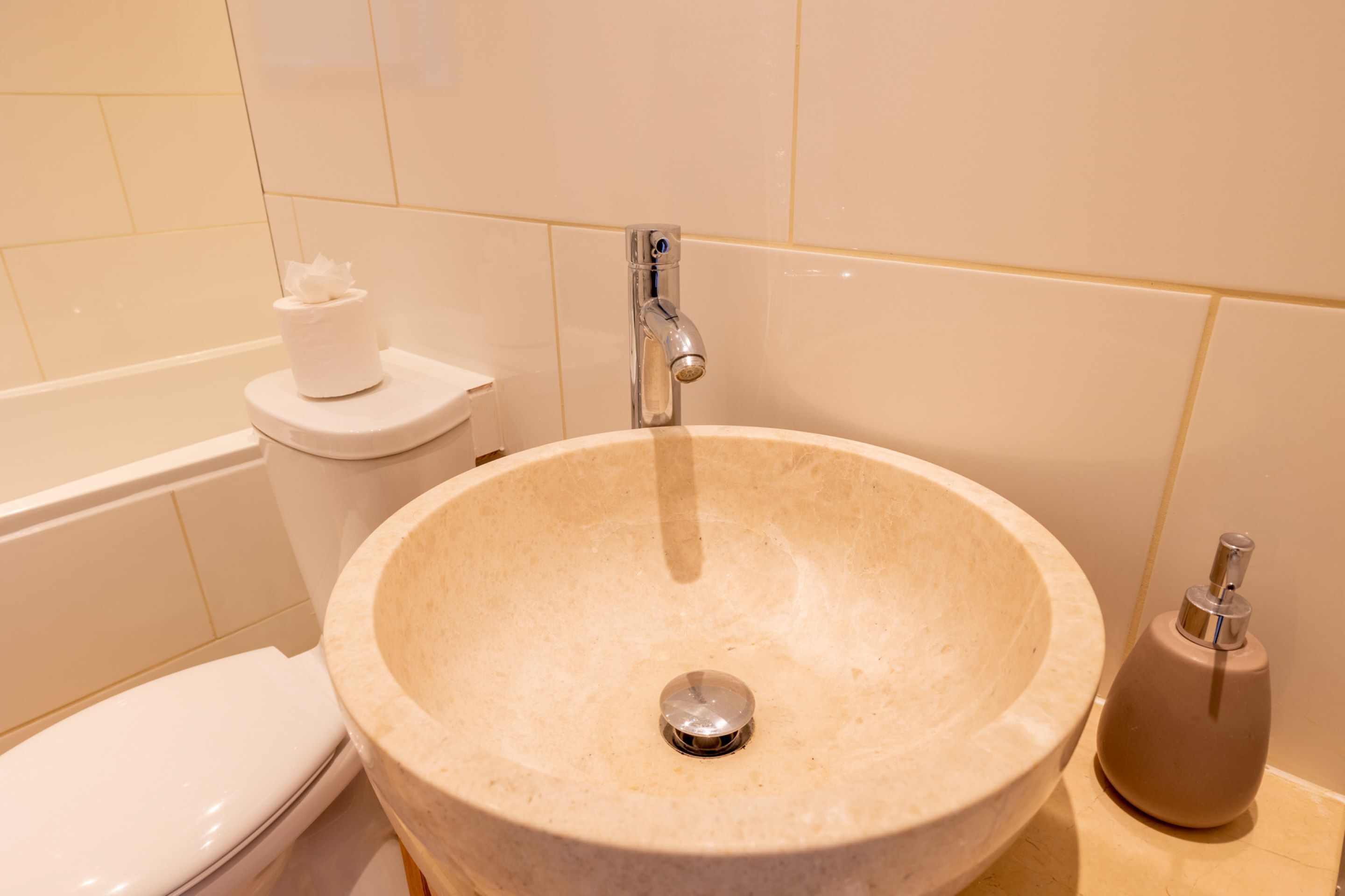 A bathroom with a beige sink, a toilet, and a bidet.