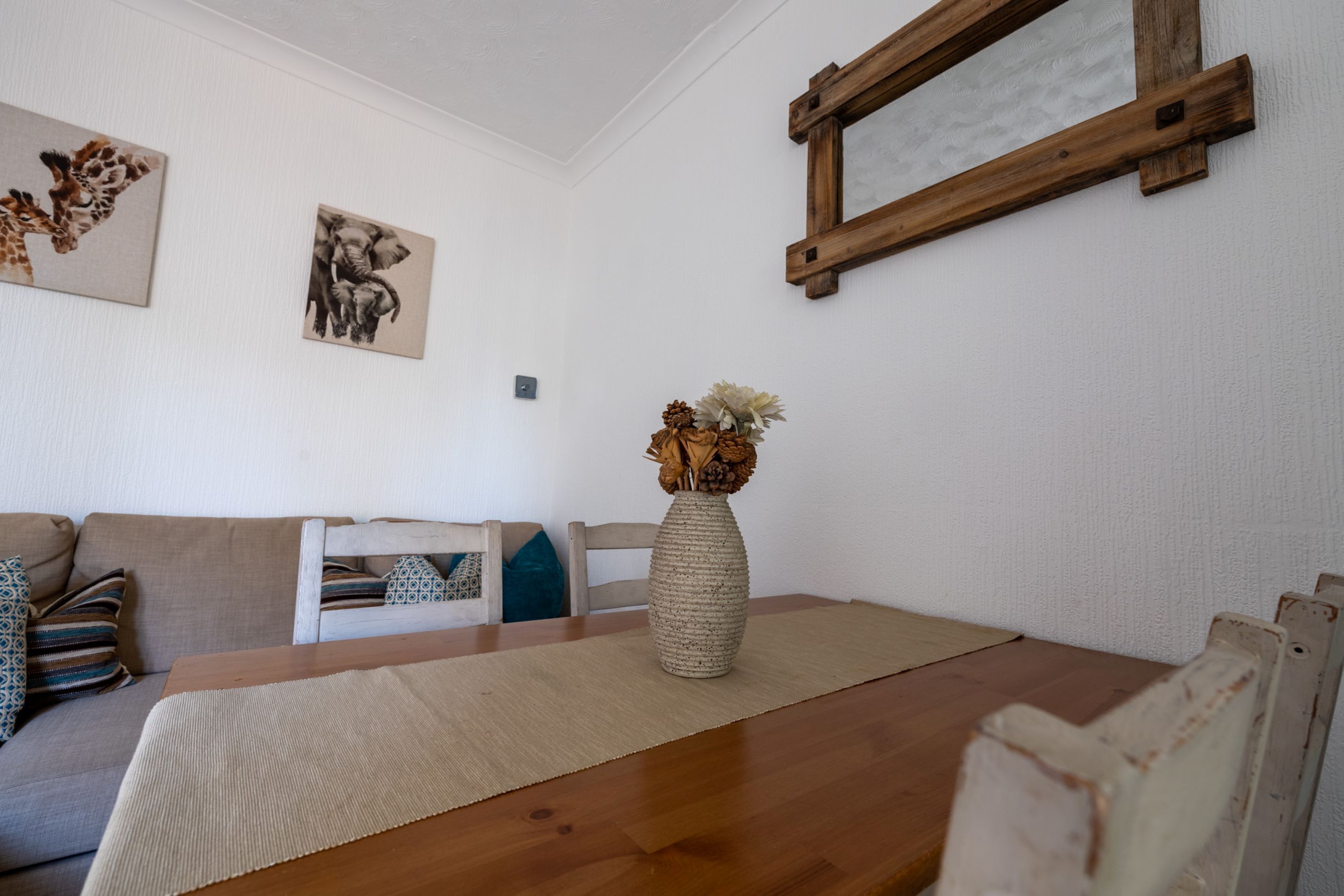 Un salon comprenant une table à manger en bois, un canapé et deux tableaux accrochés au mur.