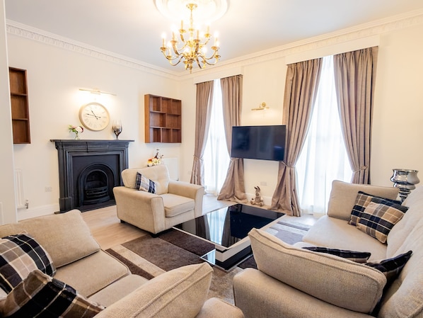 Una sala de estar con chimenea, televisor y candelabro.