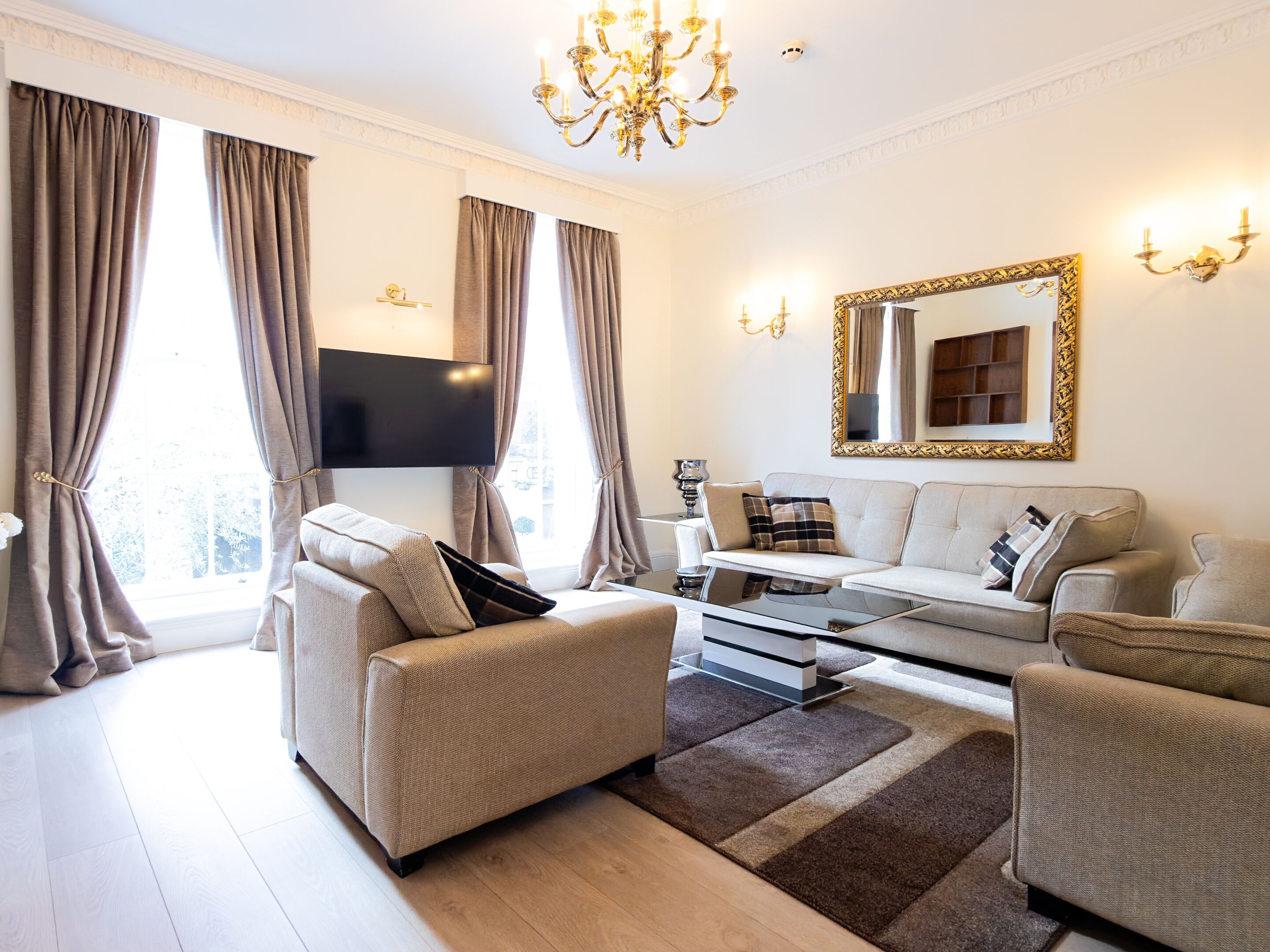 A modern living room with a sofa, armchairs, a coffee table, and a flat-screen TV.