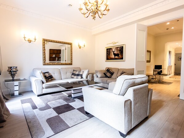 A modern living room with a sofa, coffee table, and a chandelier.