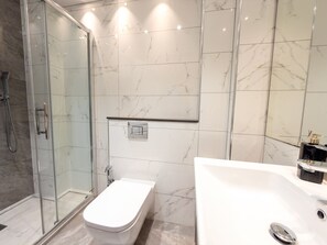Une salle de bain moderne avec une douche à parois de verre, des toilettes séparées et un grand lavabo blanc avec un miroir.