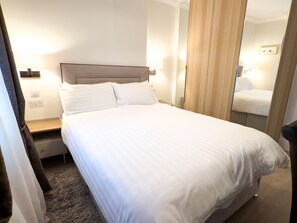 Un lit bien fait, avec du linge de lit blanc, dans une chambre d'hôtel.