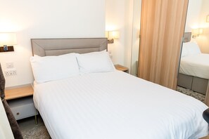 A neatly made bed with white linens, a wooden headboard, and bedside lamps. - Chic 1 bedroom apartment in Marylebone (London)