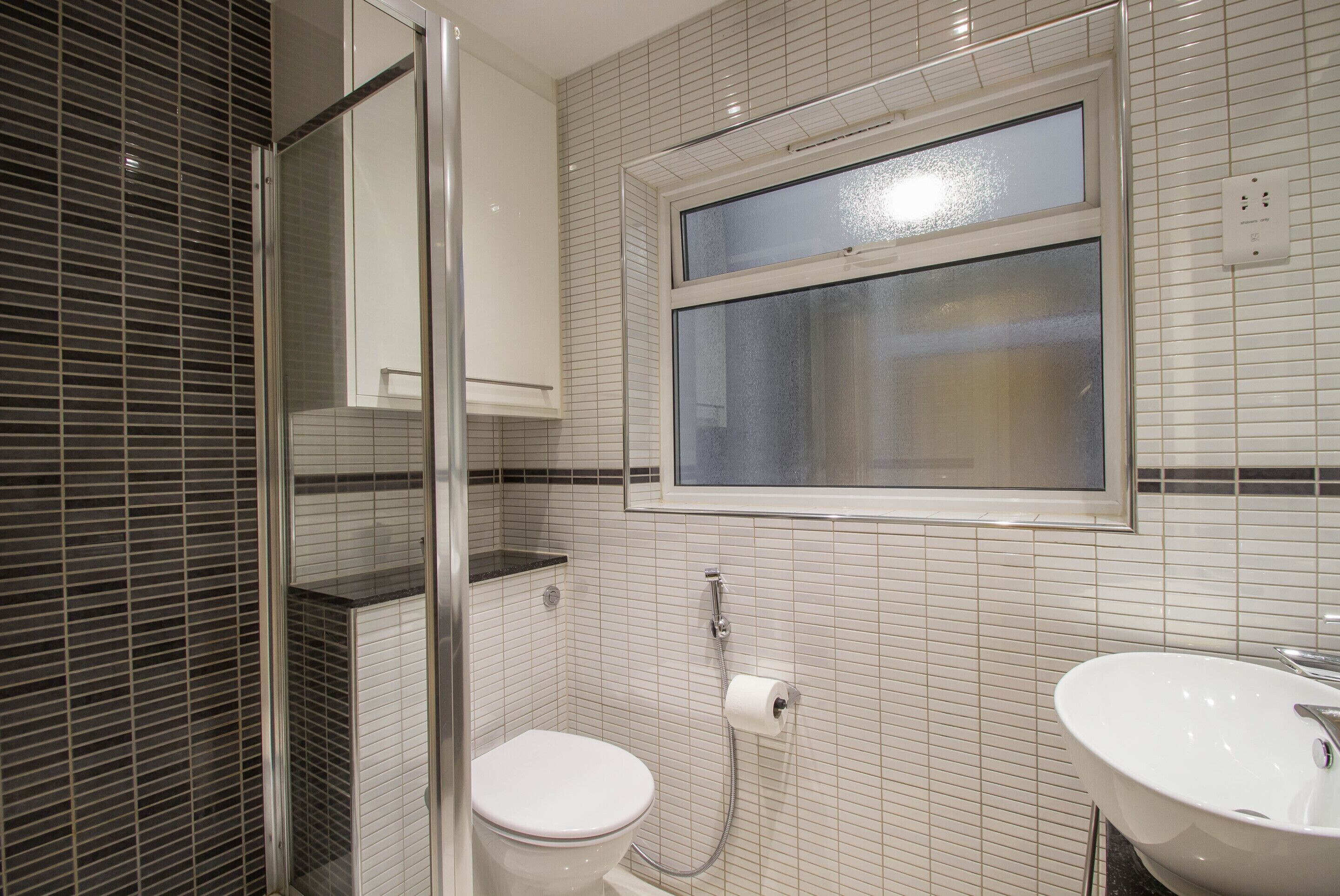 A bathroom with a toilet, a sink, a shower, and a window.